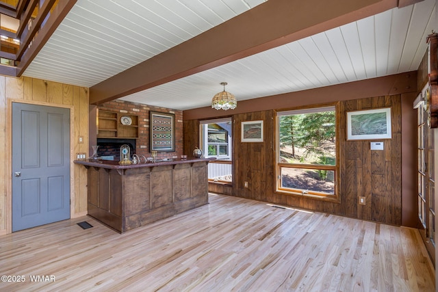 38684 State Route 373, Greer, AZ 85927 - kitchen with wood walls, light wood-type flooring, beamed ceiling, a peninsula, and a chandelier