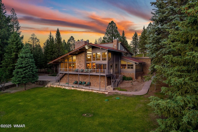 38684 State Route 373, Greer, AZ 85927 - back of house at dusk with stairway, a chimney, stone siding, a patio area, and a yard