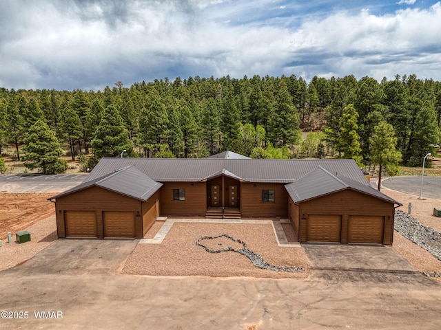 4696 W Tatanka Loop, Show Low, AZ 85901 - view of front of property with an attached garage, asphalt driveway, a wooded view, and metal roof