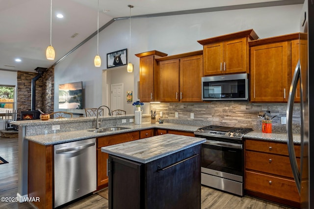 721 S Reynolds Ln, Show Low, AZ 85901 - kitchen featuring appliances with stainless steel finishes, a wood stove, a peninsula, brown cabinets, and tasteful backsplash