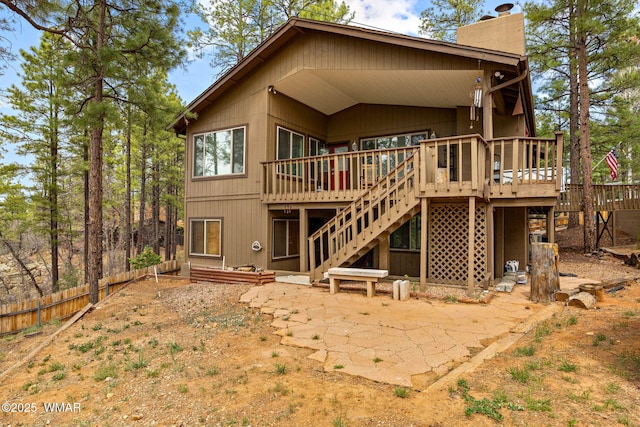 back of property with a deck, a chimney, fence, stairway, and a patio area