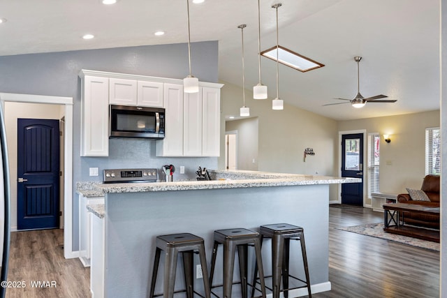 kitchen featuring appliances with stainless steel finishes, lofted ceiling, white cabinetry, dark wood-style floors, and a ceiling fan