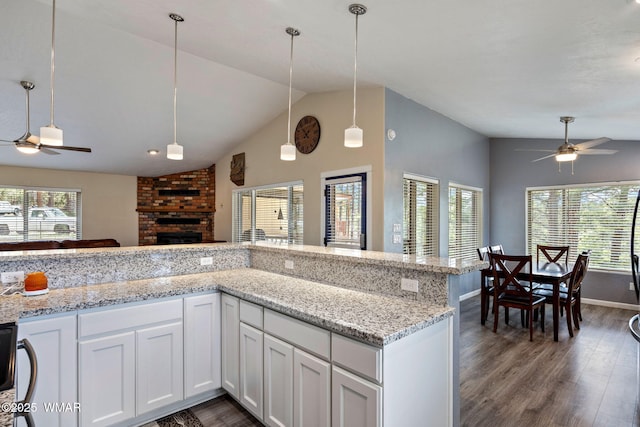 kitchen with ceiling fan, lofted ceiling, dark wood finished floors, a fireplace, and pendant lighting