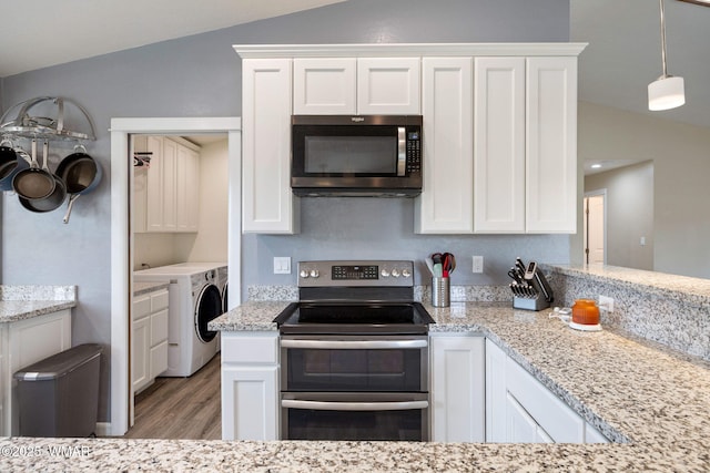 kitchen featuring vaulted ceiling, range with two ovens, wood finished floors, washer and dryer, and white cabinetry