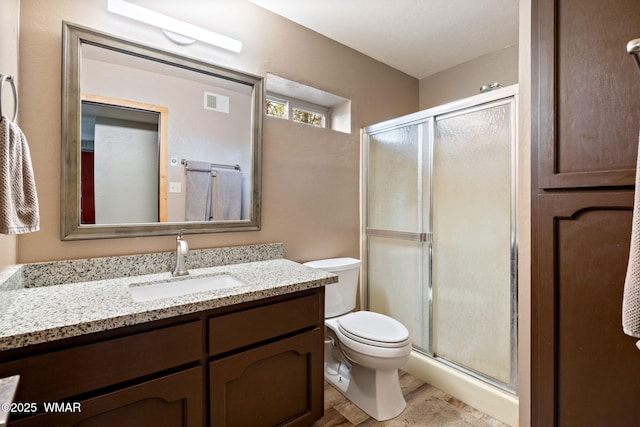 bathroom with a stall shower, toilet, vanity, and wood finished floors