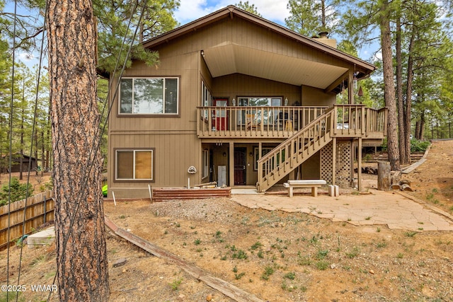back of house featuring a wooden deck, stairway, fence, and a chimney