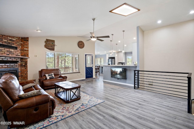 living area with a brick fireplace, healthy amount of natural light, wood finished floors, ceiling fan, and recessed lighting