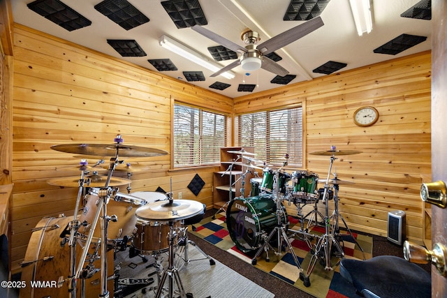 recreation room featuring ceiling fan and wooden walls