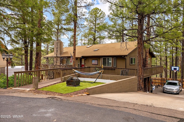 view of front of house featuring a chimney, an outdoor fire pit, roof with shingles, and a wooden deck