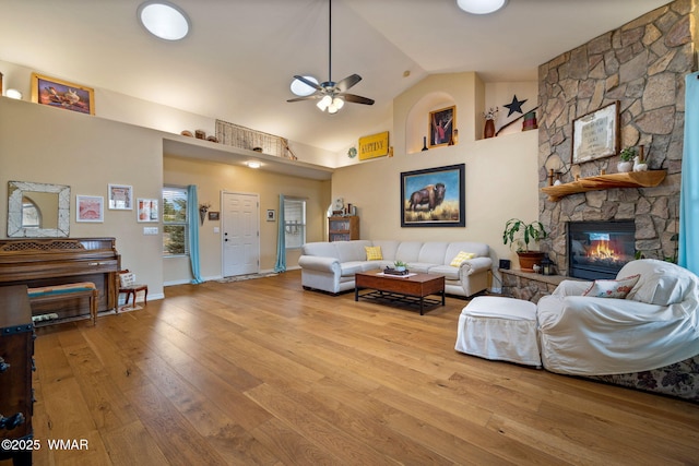 living room with high vaulted ceiling, wood-type flooring, a fireplace, baseboards, and ceiling fan