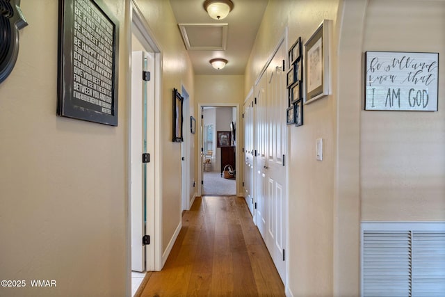 hallway with visible vents, baseboards, and wood finished floors