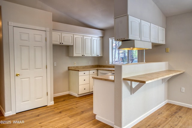 880 N 46th Dr, Show Low, AZ 85901 - kitchen featuring a peninsula, white cabinets, light wood-type flooring, lofted ceiling, and a kitchen bar
