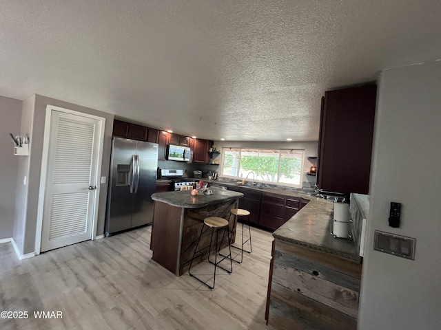 8515 Pueblo Ln, Snowflake, AZ 85937 - kitchen featuring appliances with stainless steel finishes, open shelves, light wood-type flooring, a textured ceiling, and a breakfast bar area