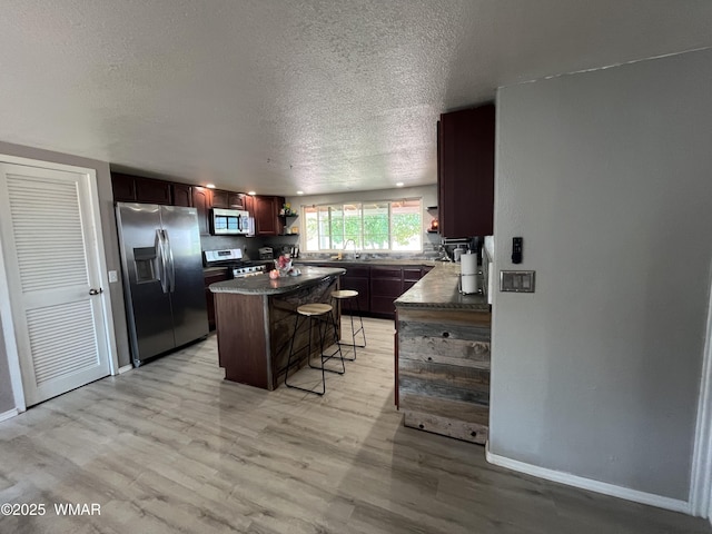 8515 Pueblo Ln, Snowflake, AZ 85937 - kitchen with open shelves, appliances with stainless steel finishes, dark countertops, a textured ceiling, and a breakfast bar area