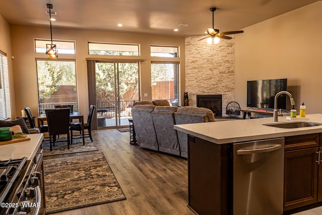 kitchen featuring dark wood finished floors, open floor plan, a sink, and a stone fireplace