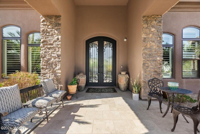 property entrance with stone siding, french doors, and stucco siding