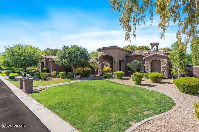 mediterranean / spanish house with a front yard, stone siding, a tile roof, and stucco siding