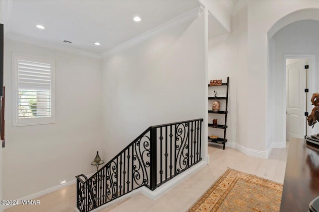 corridor featuring baseboards, arched walkways, crown molding, and an upstairs landing