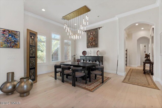 dining area featuring light wood-style floors, arched walkways, crown molding, and baseboards