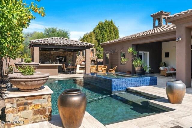 pool with a gazebo, an outdoor living space with a fireplace, and an in ground hot tub