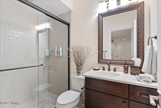 bathroom with a ceiling fan, a stall shower, vanity, and toilet