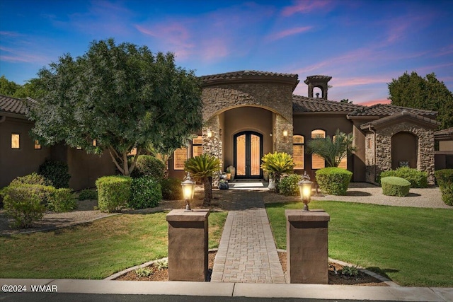 mediterranean / spanish home with stone siding, french doors, a tile roof, and stucco siding