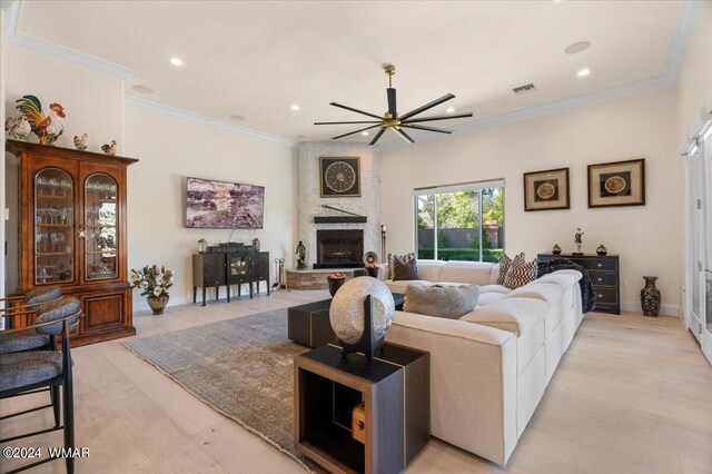 living room featuring a large fireplace, recessed lighting, baseboards, and crown molding