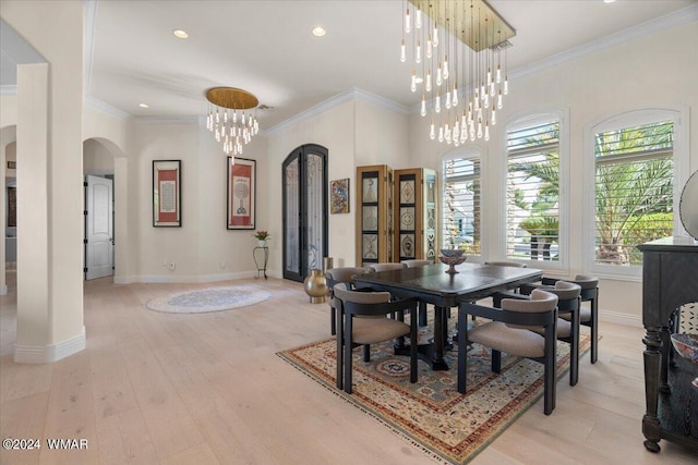 dining room with arched walkways, a notable chandelier, baseboards, light wood-type flooring, and crown molding