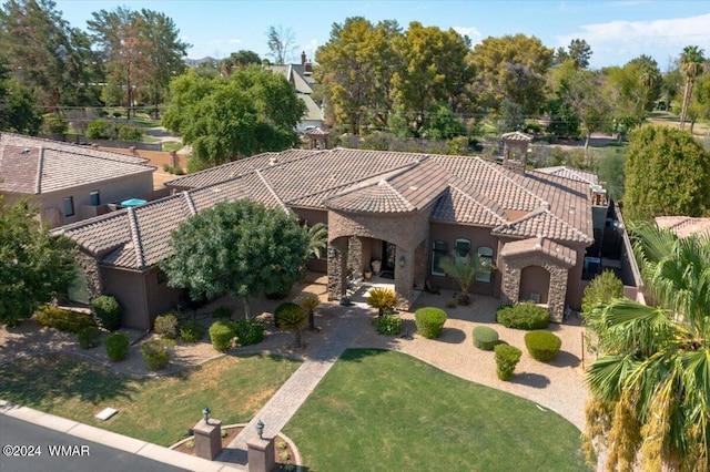 view of front of property with stone siding, a front yard, a tile roof, and stucco siding