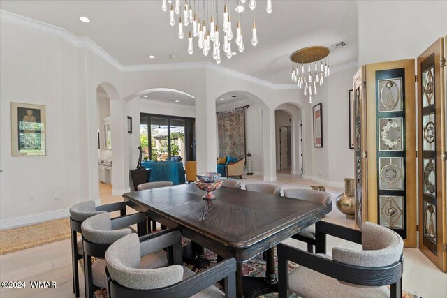 dining room with visible vents, arched walkways, baseboards, ornamental molding, and light wood-type flooring