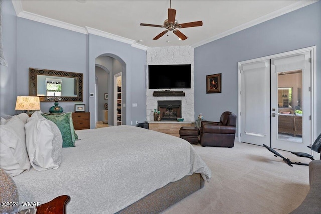 bedroom featuring carpet floors, arched walkways, ornamental molding, a ceiling fan, and a stone fireplace