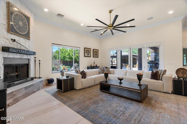 living room featuring visible vents, crown molding, light wood-style floors, a fireplace, and recessed lighting