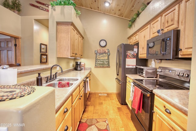 kitchen featuring light brown cabinetry, stainless steel appliances, a sink, and light wood-type flooring