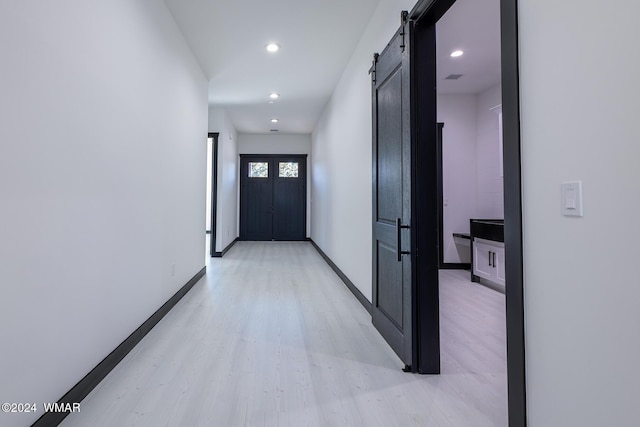 hall featuring light wood-type flooring, recessed lighting, baseboards, and a barn door