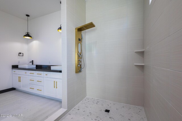 full bathroom featuring tiled shower, a sink, and double vanity