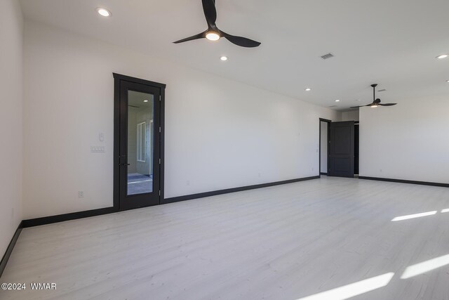 spare room with baseboards, ceiling fan, and light wood finished floors