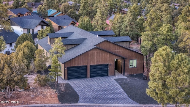 exterior space featuring a garage, decorative driveway, and roof with shingles