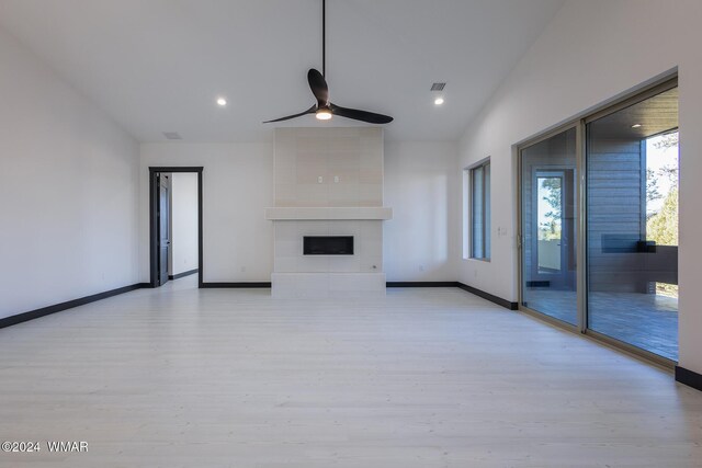 unfurnished living room featuring baseboards, light wood-style flooring, a ceiling fan, and a tiled fireplace