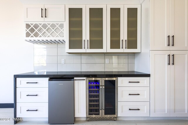 bar featuring tasteful backsplash, wine cooler, refrigerator, and a dry bar