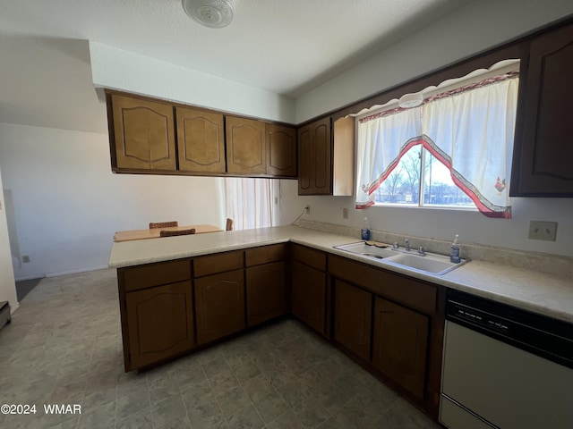 kitchen featuring a sink, a peninsula, light countertops, and dishwasher