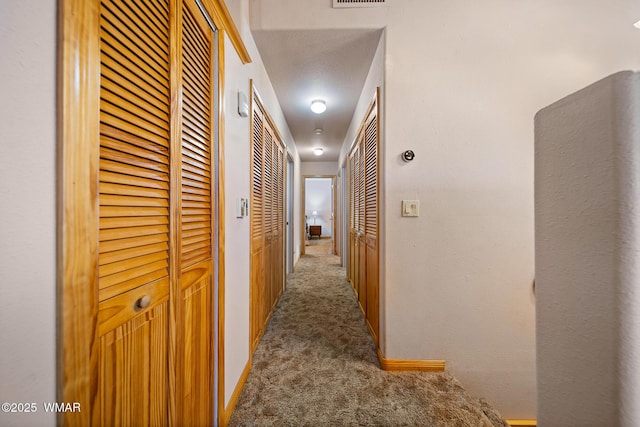 hall featuring carpet flooring and visible vents