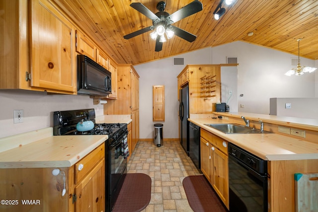kitchen with a sink, a peninsula, lofted ceiling, stone tile flooring, and black appliances