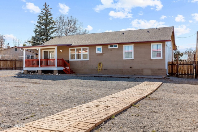 rear view of property with crawl space, roof with shingles, fence, and a deck