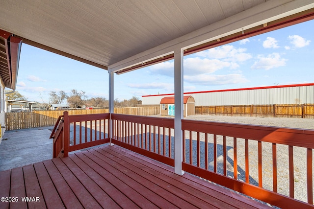 wooden deck featuring an outbuilding, a storage shed, and a fenced backyard