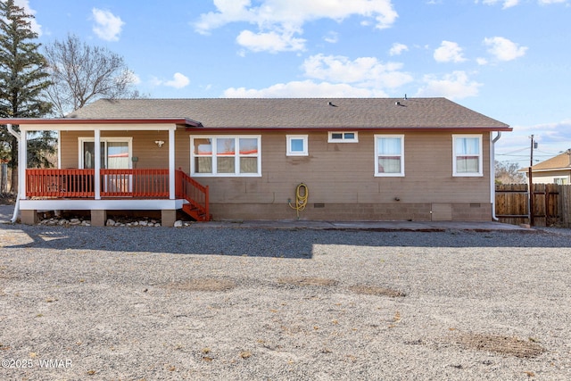 rear view of house featuring roof with shingles, a porch, crawl space, and fence