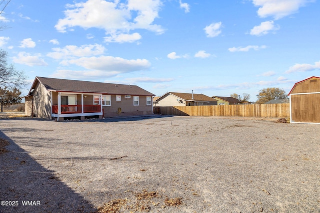 rear view of house with an outdoor structure and fence