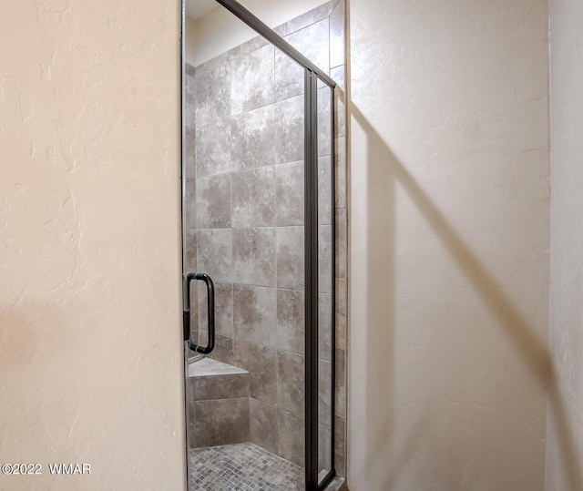 full bathroom with a textured wall and a shower stall