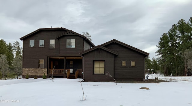 snow covered rear of property with a porch