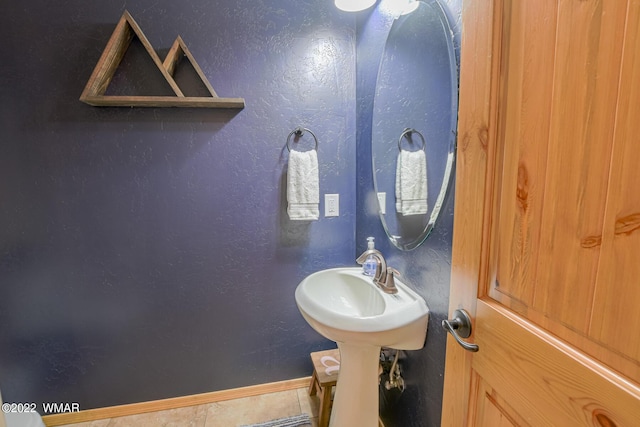 bathroom with tile patterned flooring, baseboards, and a textured wall