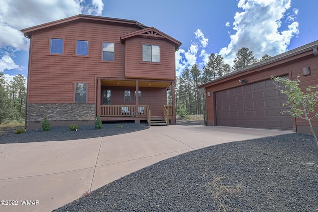 view of front facade featuring covered porch, a garage, stone siding, driveway, and crawl space